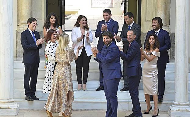 Imagen principal - El presidente López Miras aplaude al término del acto junto a todo su equipo de gobierno.| José María Albarracín, con el consejero Antonio Luengo. | Selfi de Adela Martínez-Cachá con María Esperanza Moreno. 