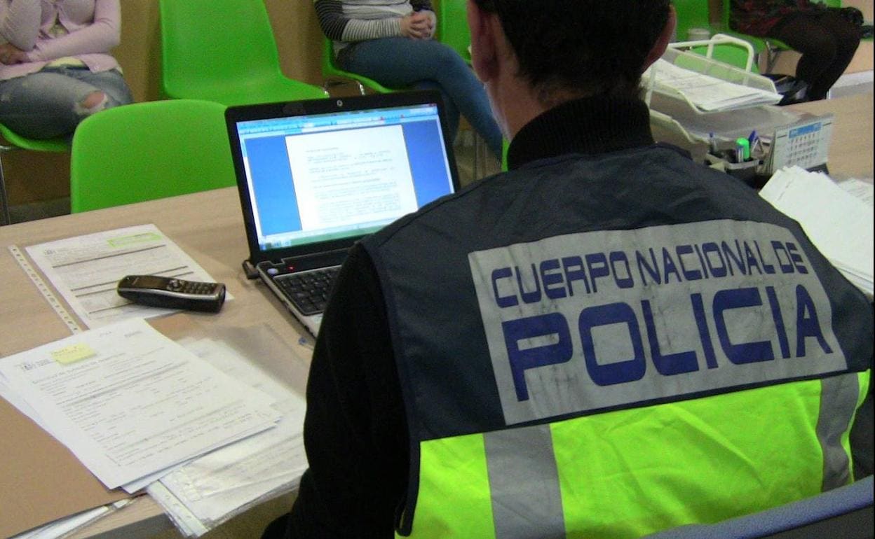 Un policía nacional consulta un ordenador en medio de una investigación.