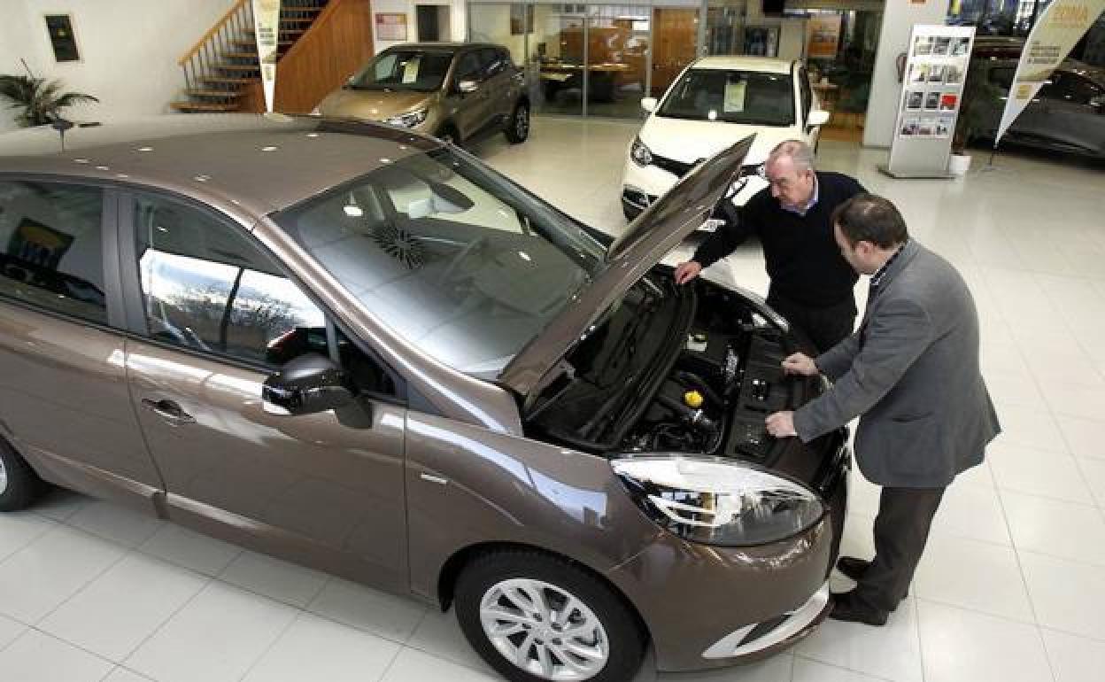 Un comercial enseña un coche a un cliente.