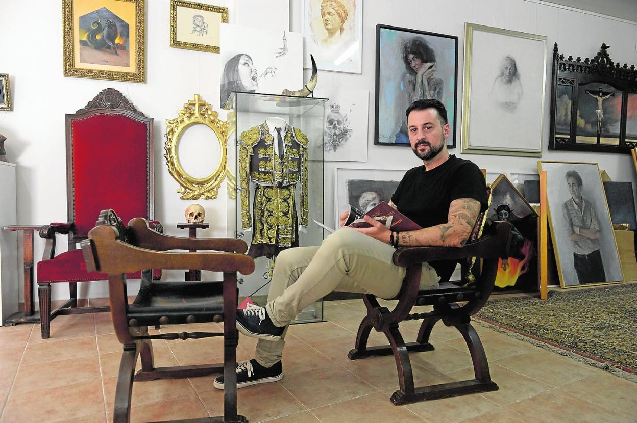 El artista Martínez Cánovas posa en su estudio de la ciudad de Murcia mientras hojea un libro de arte y toros. 