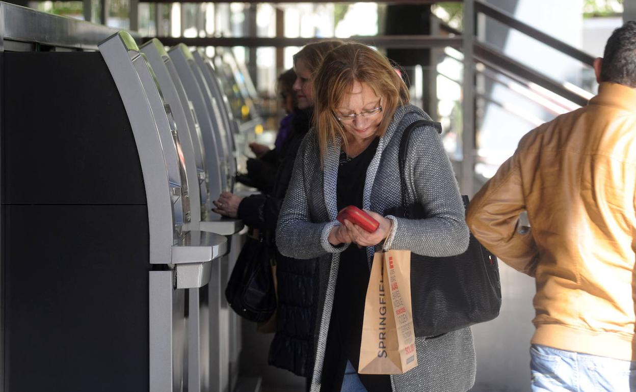 Varias personas realizan operaciones bancarias a través de cajeros automatizados.