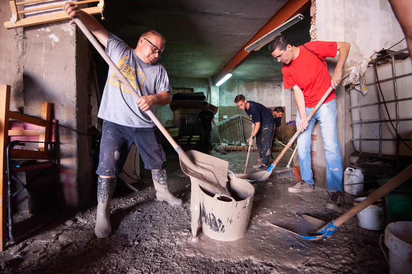 Vecinos de El Raal limpian el barro de su casa tras el paso de la gota fría.