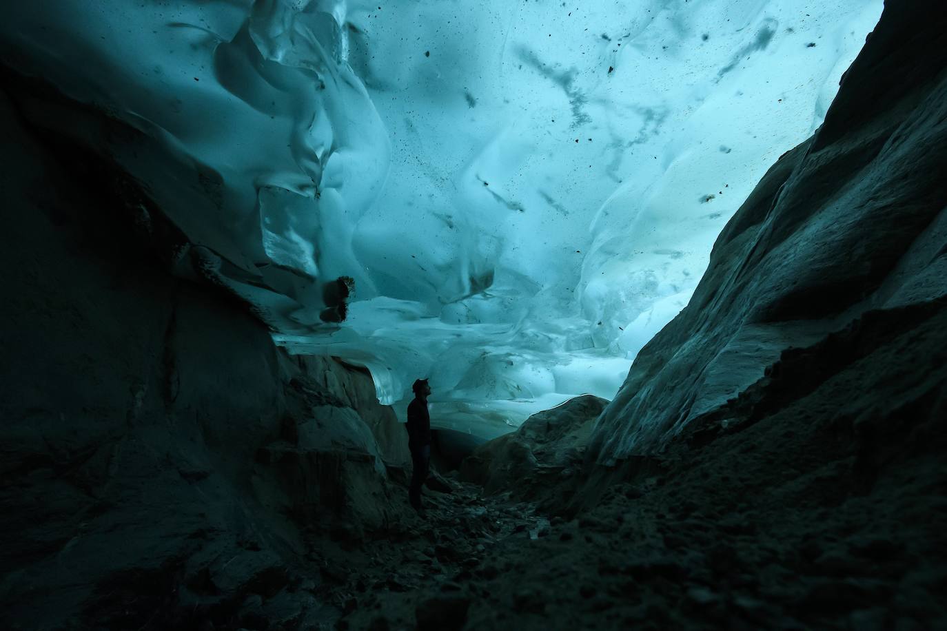 Un hombre mira el glaciar Aletsch desde una cavidad interior, en el Cantón de Valais (Suiza). El glaciar suizo Aletsch es uno más grandes de Europa y el primer lugar de los Alpes declarado Patrimonio de la Humanidad por la Unesco. Este enorme río de hielo se extiende a lo largo de 23 km desde su formación en la región de Jungfrau hasta el desfiladero de Massa, en el Cantón del Valais.