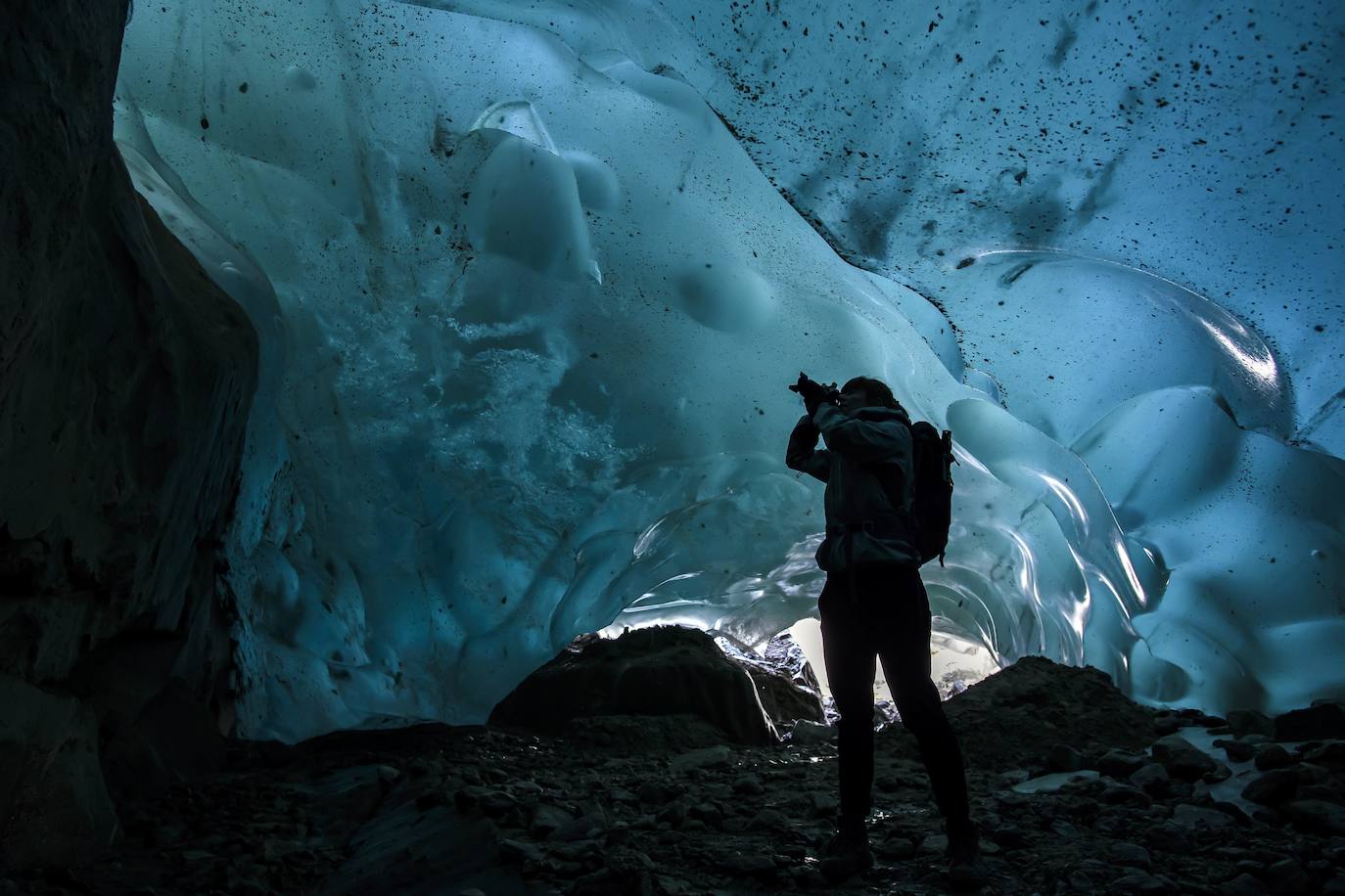 Un hombre mira el glaciar Aletsch desde una cavidad interior, en el Cantón de Valais (Suiza). El glaciar suizo Aletsch es uno más grandes de Europa y el primer lugar de los Alpes declarado Patrimonio de la Humanidad por la Unesco. Este enorme río de hielo se extiende a lo largo de 23 km desde su formación en la región de Jungfrau hasta el desfiladero de Massa, en el Cantón del Valais.