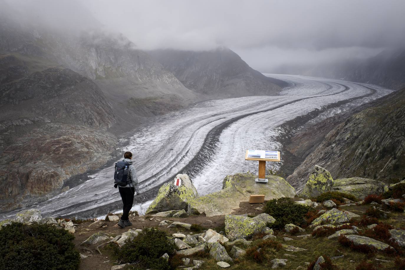 Un hombre mira el glaciar Aletsch desde una cavidad interior, en el Cantón de Valais (Suiza). El glaciar suizo Aletsch es uno más grandes de Europa y el primer lugar de los Alpes declarado Patrimonio de la Humanidad por la Unesco. Este enorme río de hielo se extiende a lo largo de 23 km desde su formación en la región de Jungfrau hasta el desfiladero de Massa, en el Cantón del Valais.