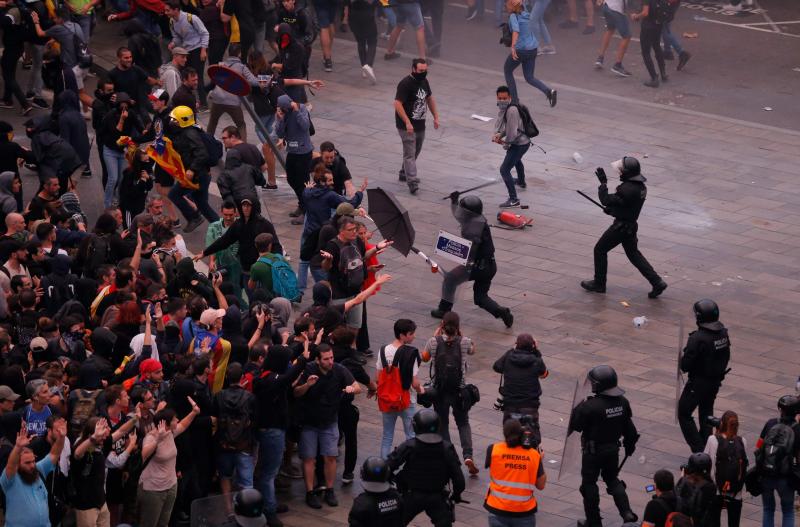 Miembros de los Mossos d'Esquadra cargan contra los centenares de personas que se agolpan ante el Aeropuerto del Prat 