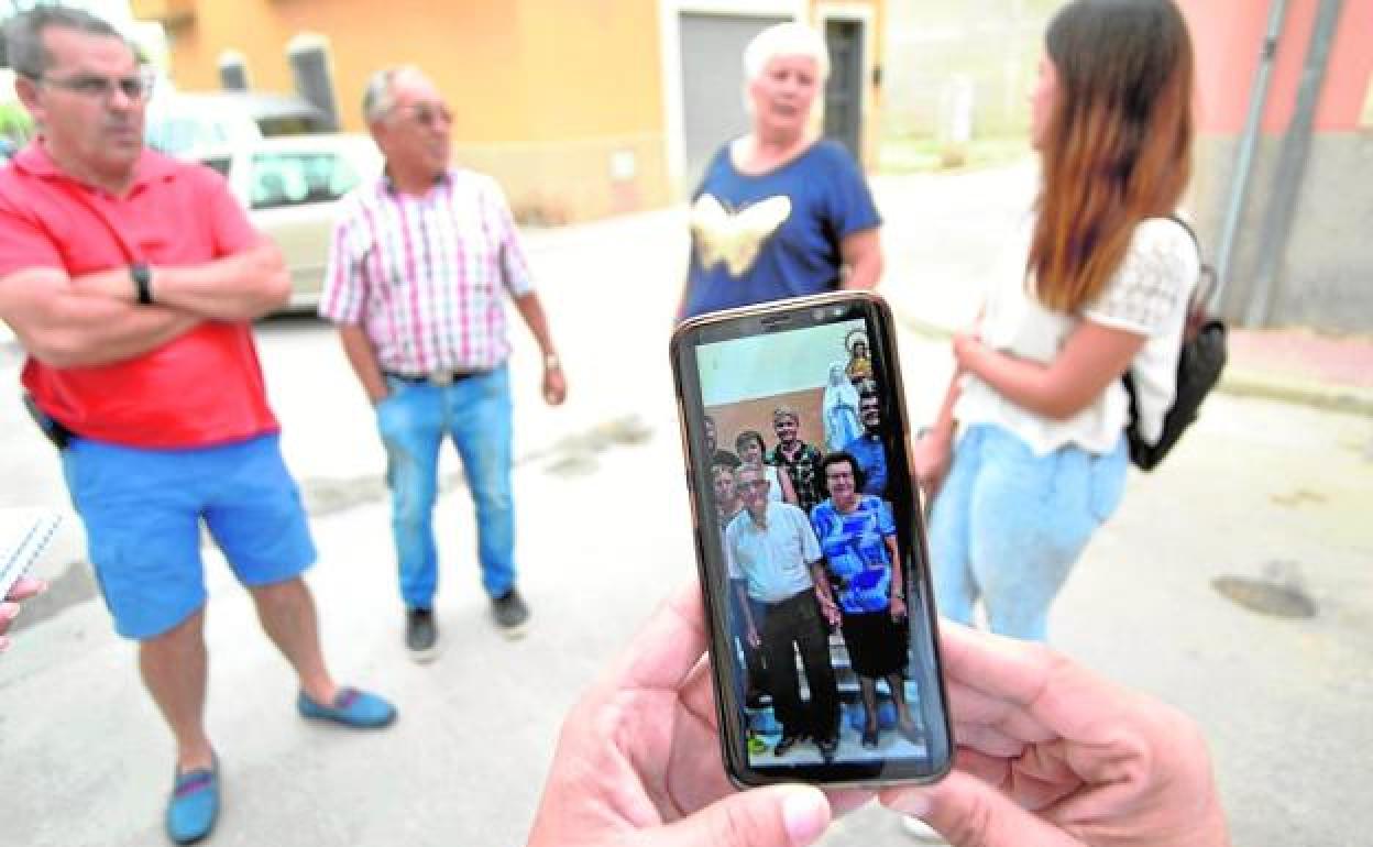 Una de las vecinas muestra una foto del matrimonio en su teléfono móvil.