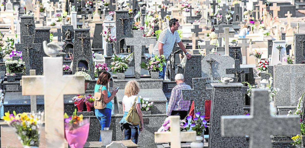 Cuatro personas entre las tumbas del cementerio de Santa Lucía, ayer, a mediodía. 