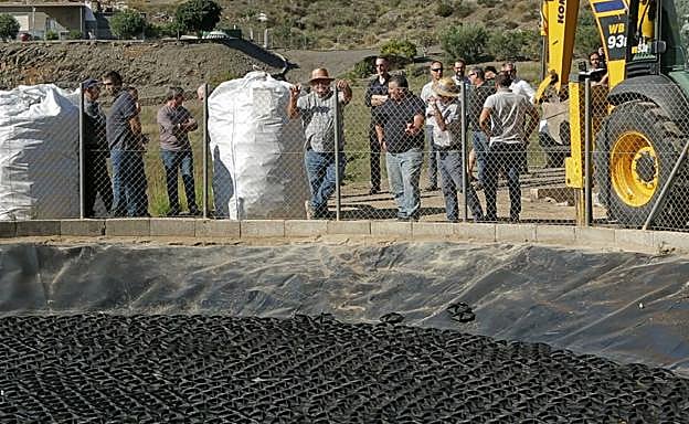 Varios profesionales del sector agrario observan los dispositivos para la mitigación de la evaporación (EMD) colocados en la balsa. 