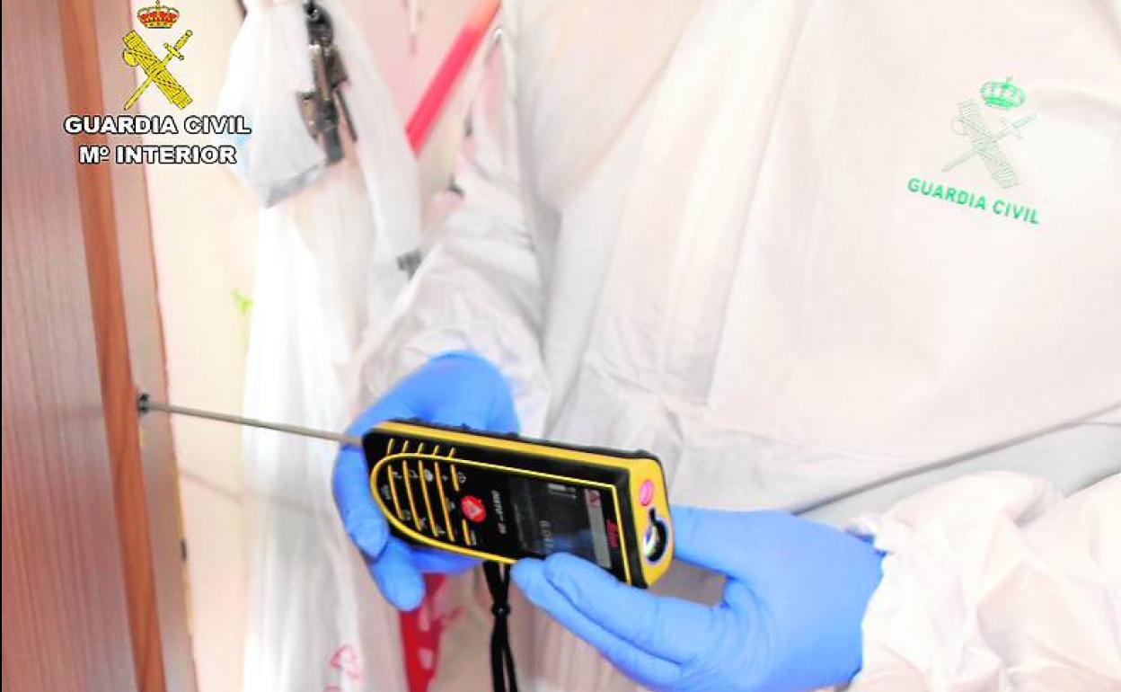 Un agente de la Policía Científica analiza la trayectoria de un disparo que atravesó la puerta de la casa de Yéchar.