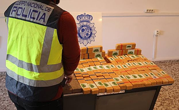 Un agente de Policía junto a la droga incautada.