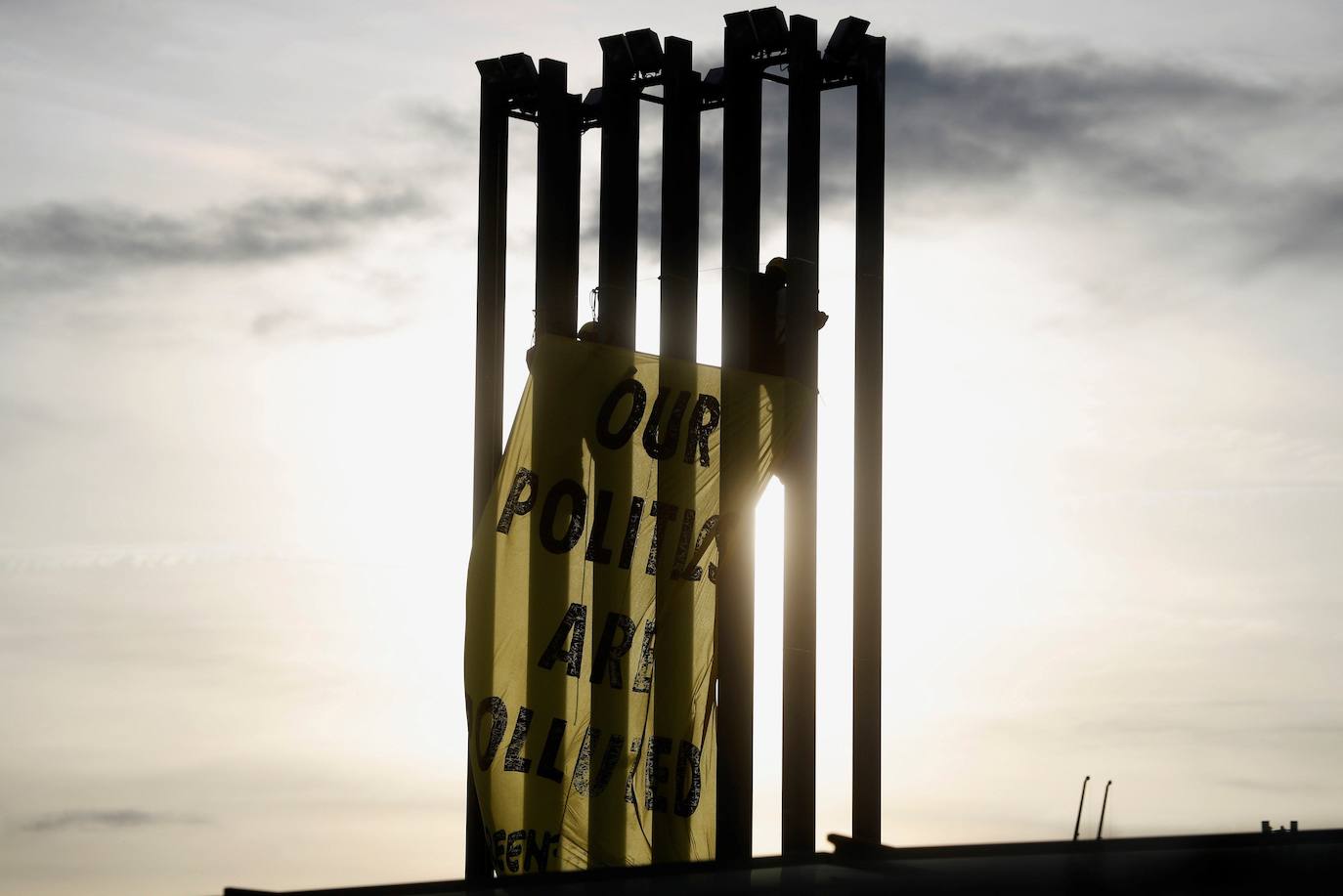 Varios activistas de Greenpeace despliegan una pancarta en una torre de iluminación del recinto ferial IFEMA