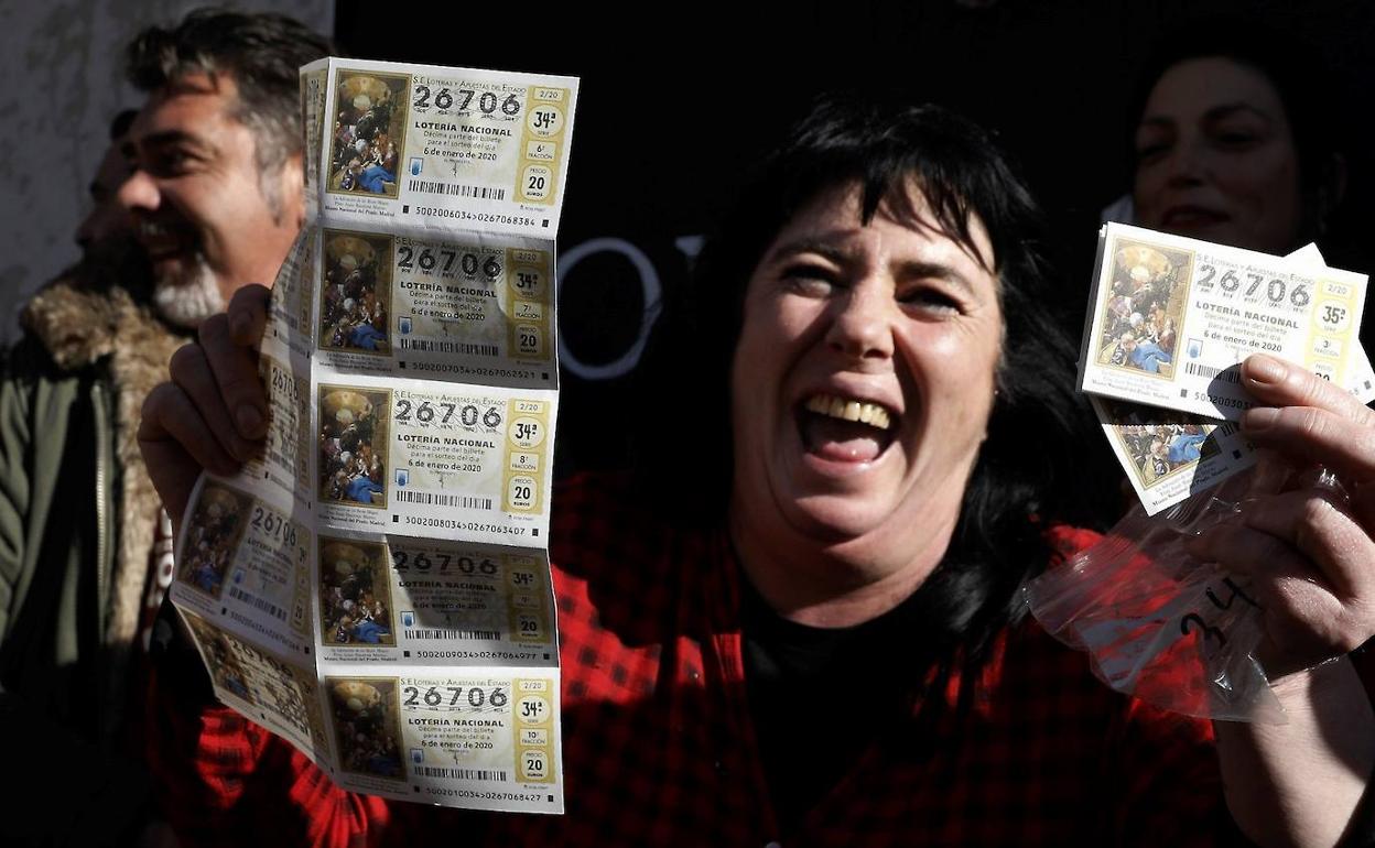 Varias personas festejan con sus décimos el tercer premio del Sorteo extraordinario de El Niño, el 26706, en Torrent, Valencia.