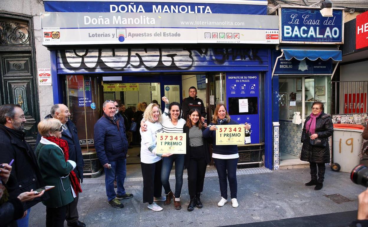 Un grupo de personas celebra el primer premio en la administración de Lotería Doña Manolita.
