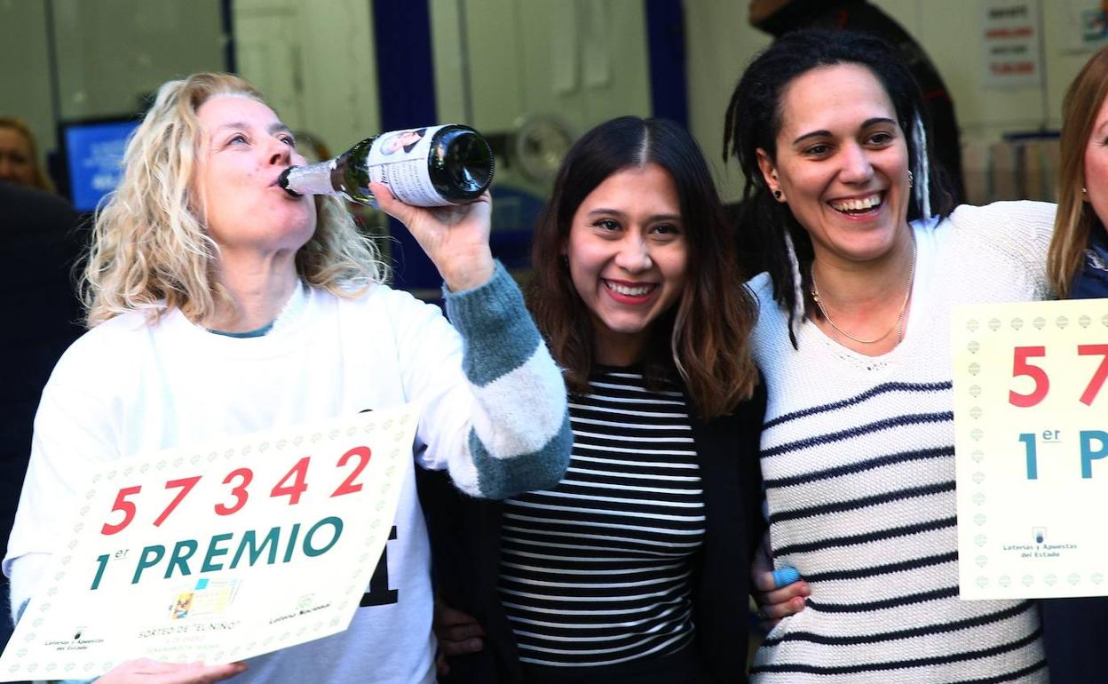 Un grupo de personas celebra el primer premio en la administración de Lotería Doña Manolita, que ha vendido diez décimos del número 57.342.