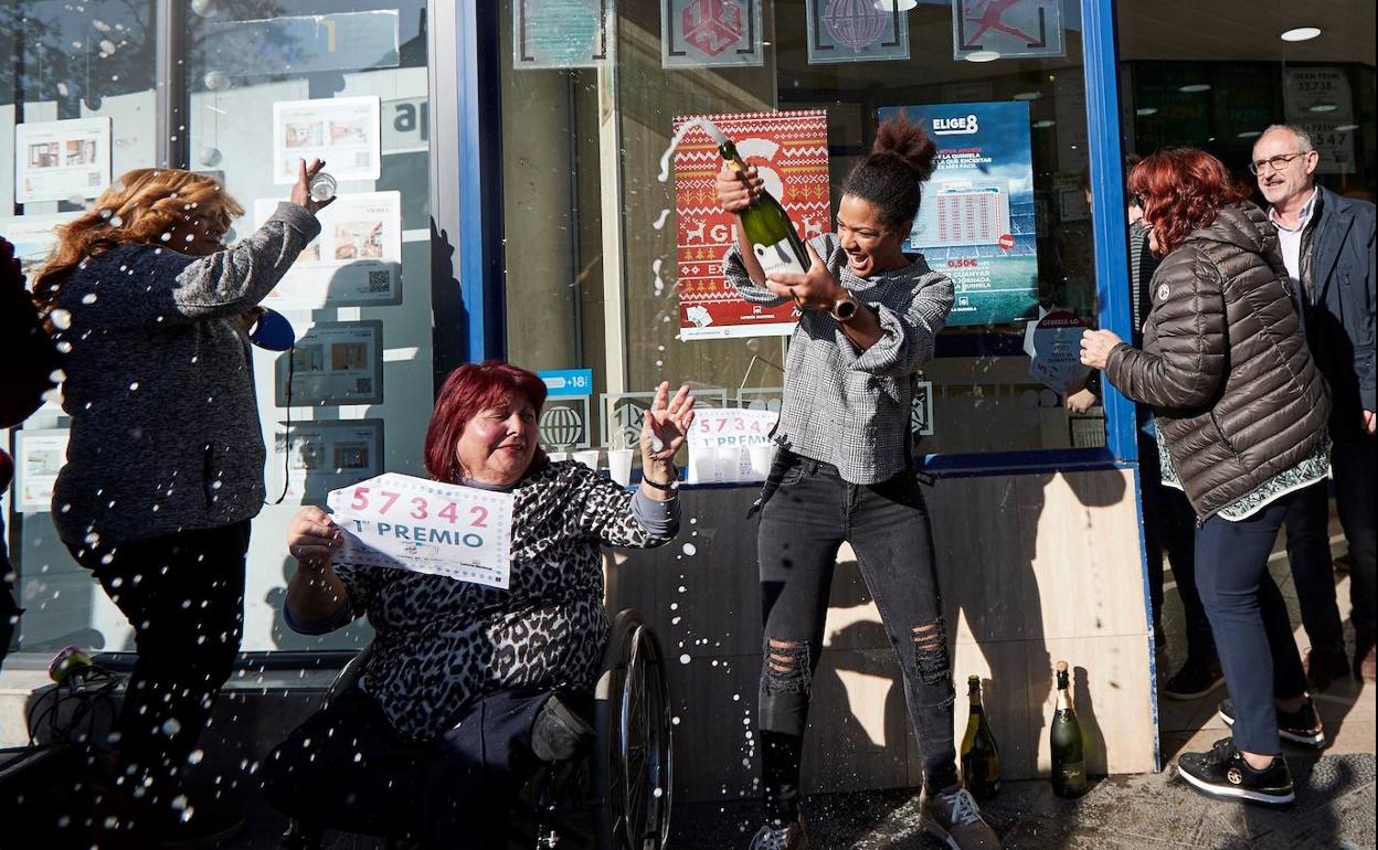 Varias personas festejan el primer premio del Sorteo extraordinario de El Niño, en la puerta de la administración de lotería de Mollet del Vallés.