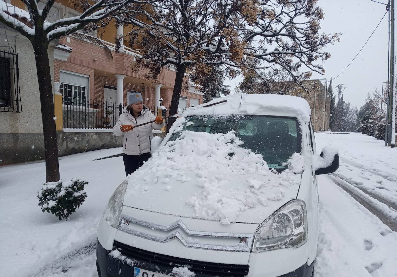 Una vecina de Archivel retira la nieve acumulada sobre su vehículo.