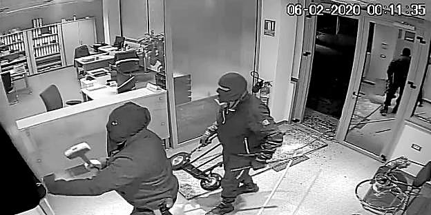 Los ladrones, con el rostro oculto con capuchas, irrumpen en una empresa tras reventar la puerta de acceso.