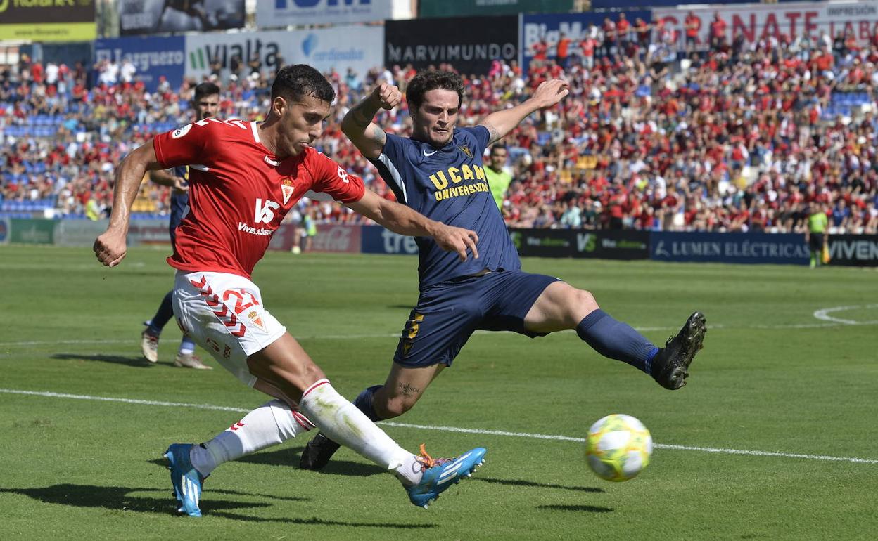 Álvaro Rodríguez golpea el balón ante el acoso de Cristian Galas., en el partido de ida de esta temporada entre Real Murcia y UCAM.