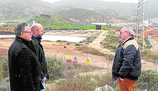 José Matías Peñas, entre los vecinos de Torreciega Pedro Gálvez y Teodosio Romero, ante unas antiguas balsas de Zinsa. Al fondo, estructura con el cohete antiaves. 