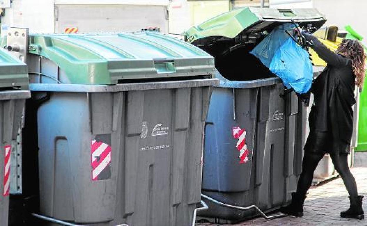Una vecina de Cartagena tira una bolsa en un contenedor de basura.