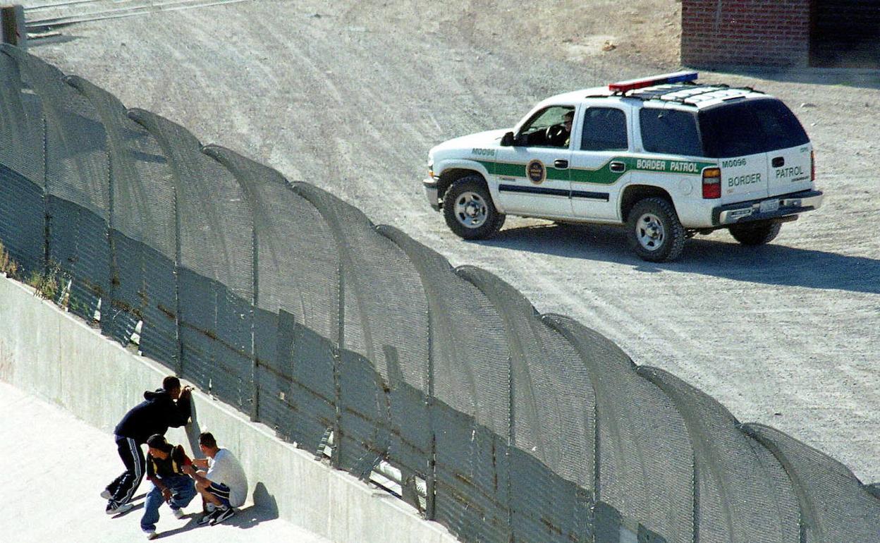 Unos inmigrantes observan a una patrulla fronteriza de EE UU desde el lado mexicano.