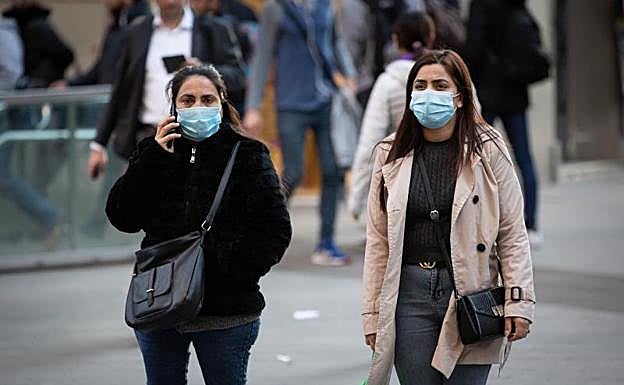 Transeúntes por el centro de Barcelona con mascarillas.