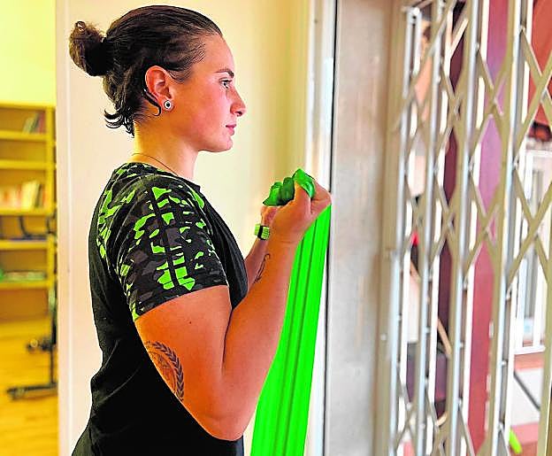 La piloto ceheginera Ana Carrasco hace estiramientos con cintas, mirando por la ventana de su casa. 
