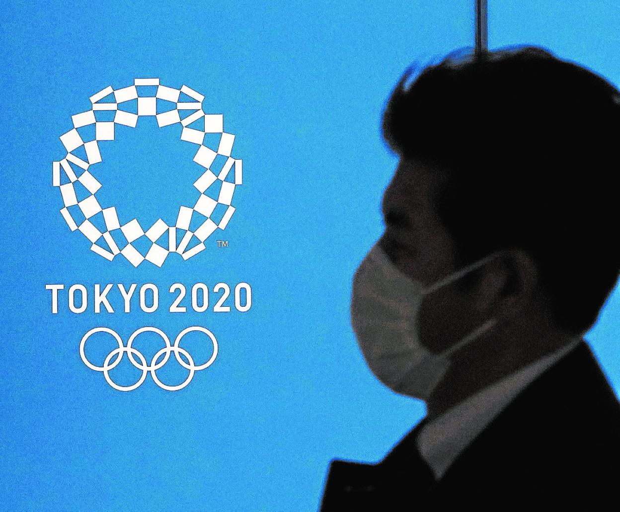 Un ciudadano japonés con mascarilla pasea por Tokio frente al emblema de los Juegos Olímpicos de 2020. 