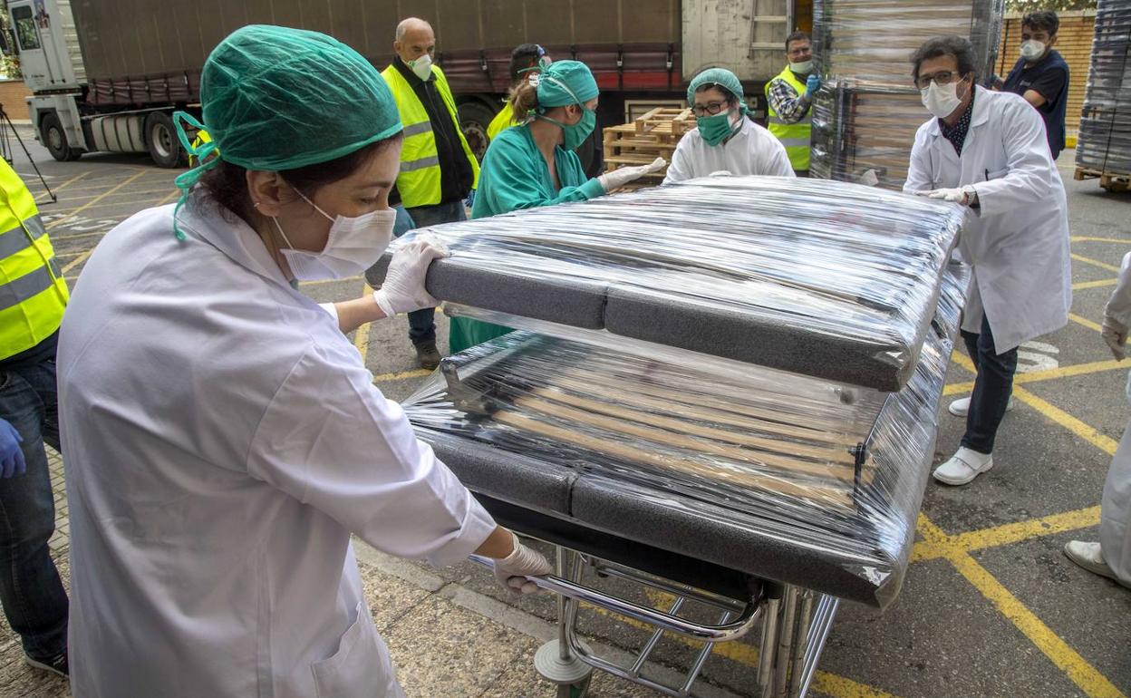 Sanitarios del hospital Rosell descargan las camas hospitalarias recibidas este viernes.