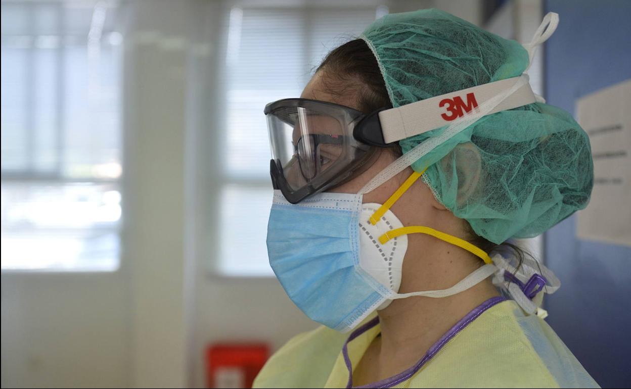 Una enfermera con una mascarilla y unas gafas de protección.