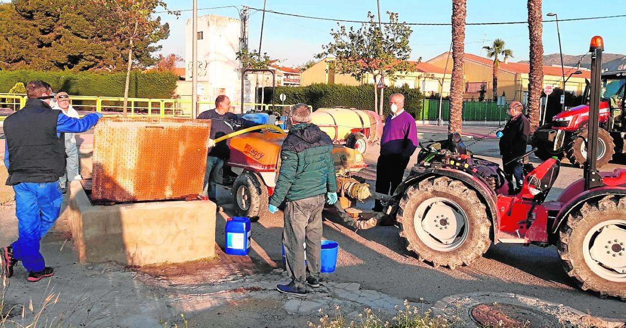 Agricultores muleños cargan las cisternas con las que desinfectan las calles. 