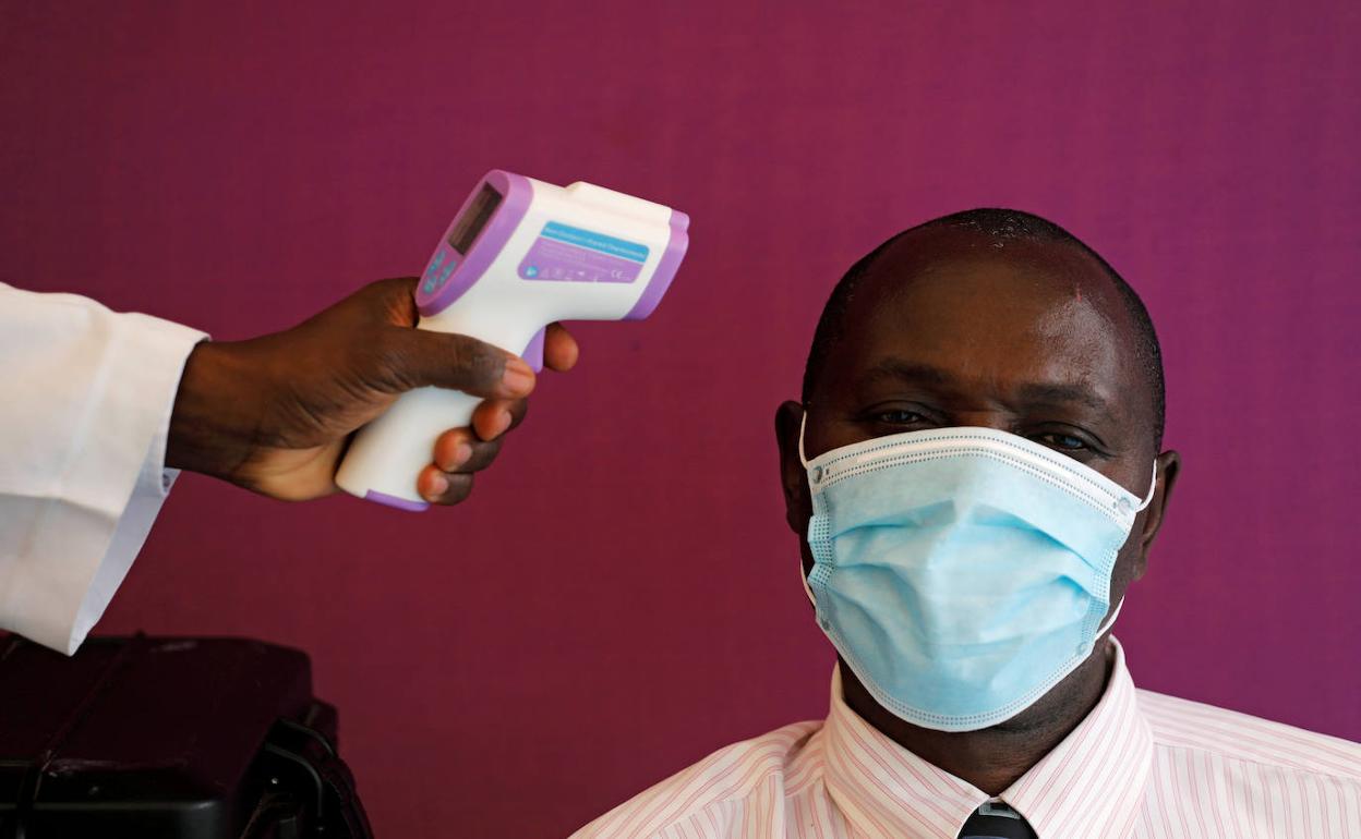 Un sanitario toma la temperatura a un hombre en Kenia.