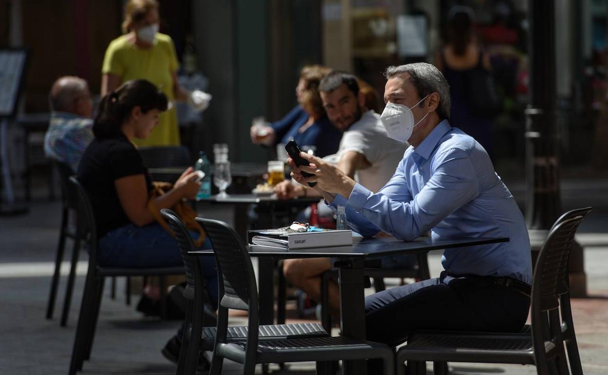 Un hombre con mascarilla sentado en la terraza de un bar del centro de Murcia, este lunes.