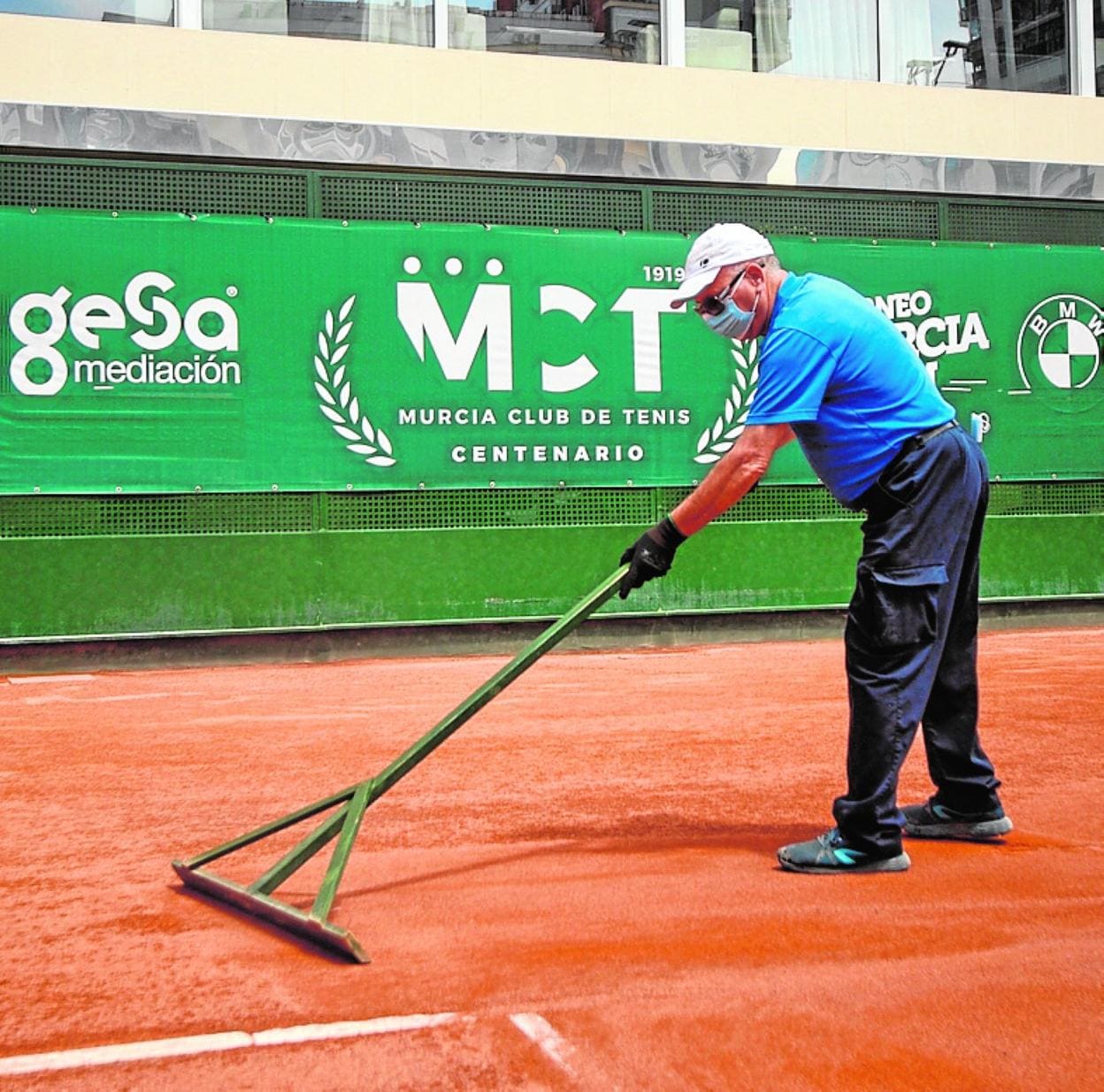 Un operario alisa una pista del Murcia Club de Tenis. 