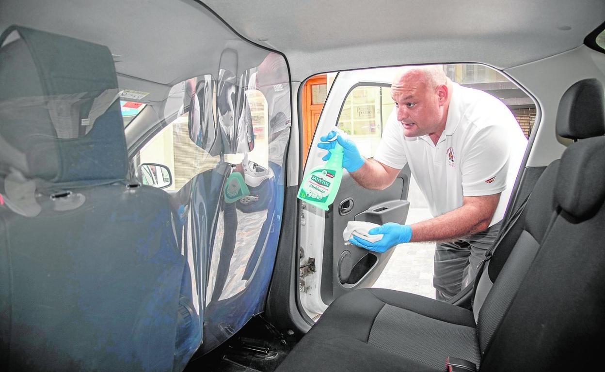 Fulgencio García limpia la mampara con gel hidroalcohólico, ayer, mientras espera clientes. 