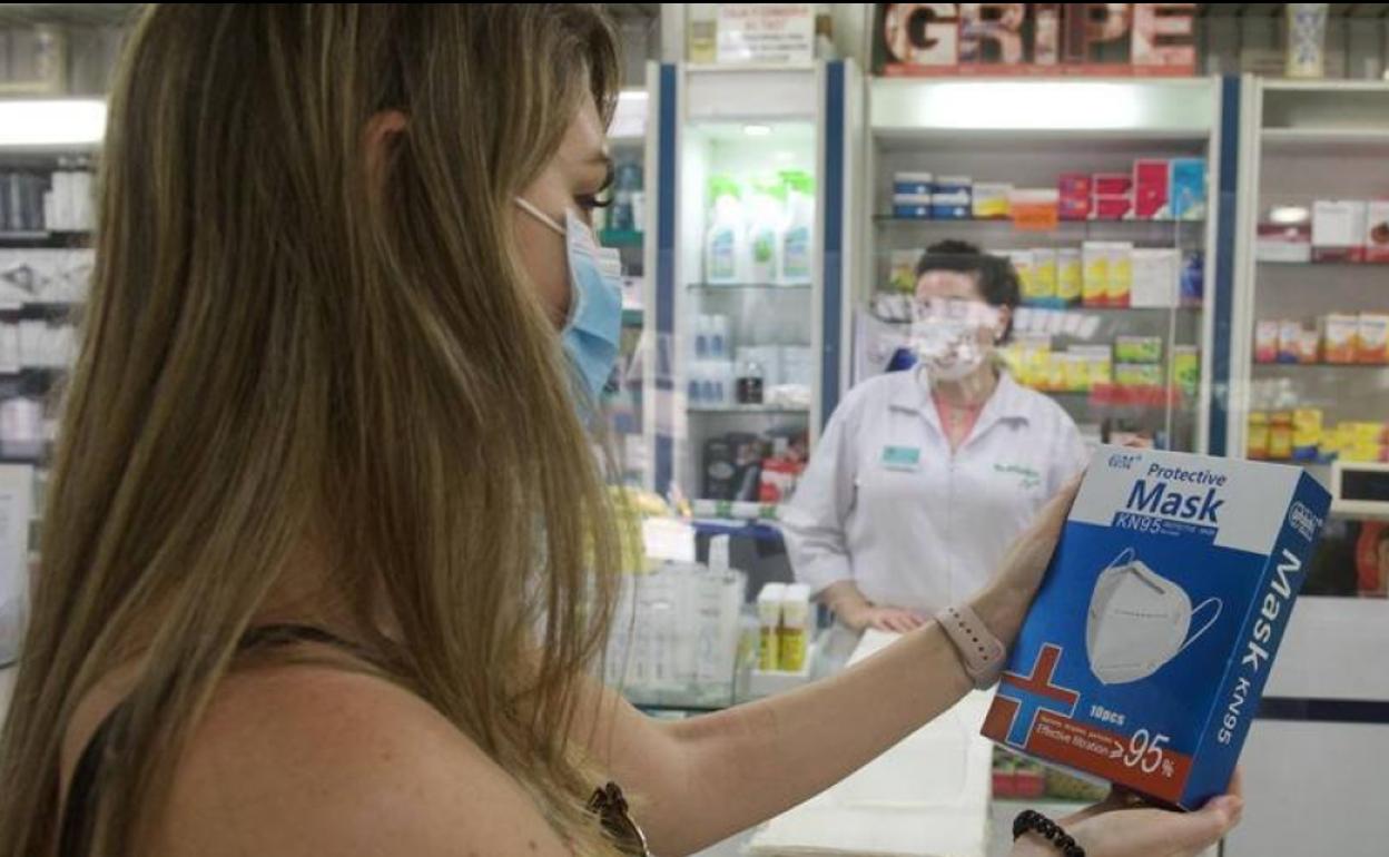 Una mujer mira una mascarilla en una farmacia.