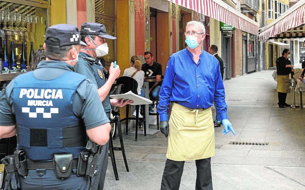 Dos agentes controlan el cumplimiento de las medidas de distanciamiento social en una terraza. 