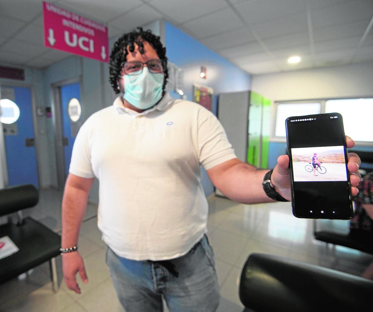 Jorge muestra una foto de su padre a las puertas de la UCI del hospital Reina Sofía, justo antes de entrar para visitarlo. 