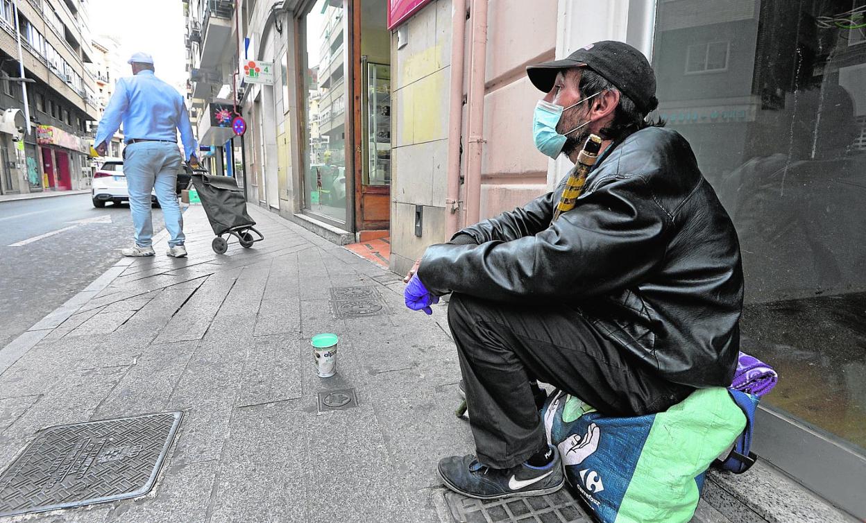 Un hombre, protegido con mascarilla, pide limosna en una calle de Murcia. 