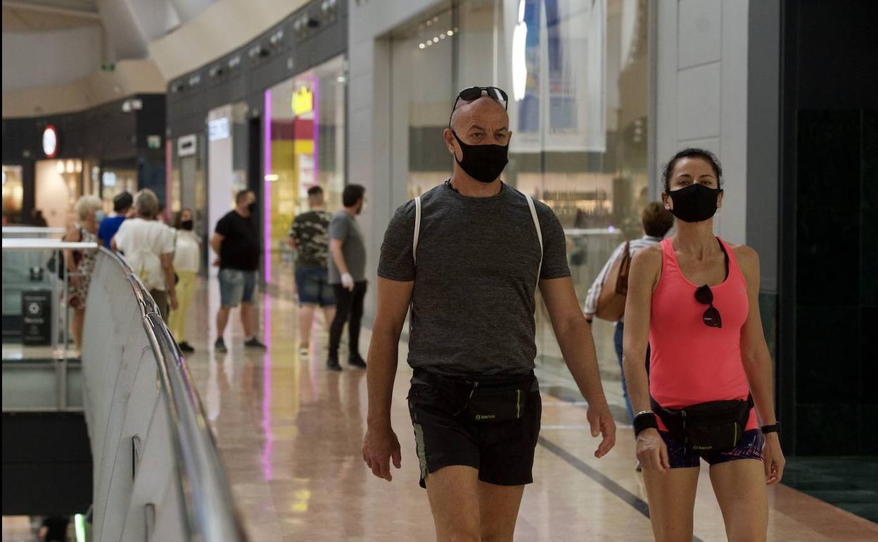 Dos personas pasean por el centro comercial Nueva Condomina.