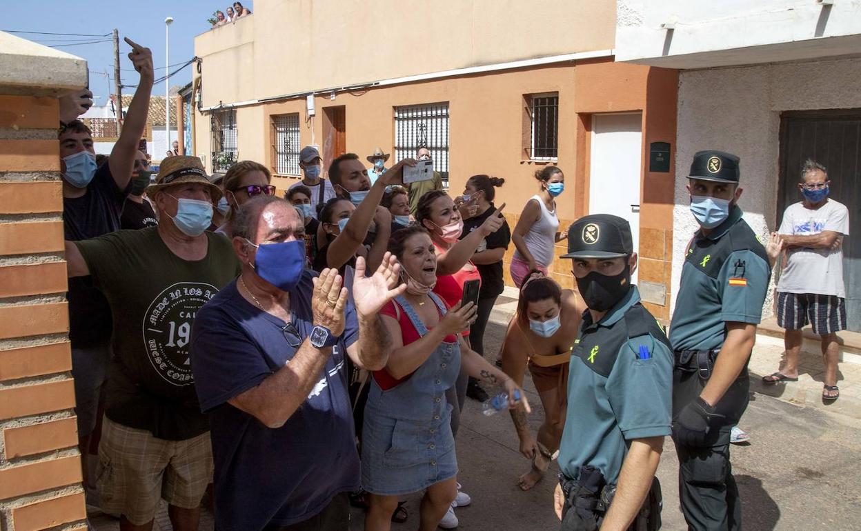 Guardias civiles contienen a los vecinos mientras se dirigen con gritos a los inmigrantes.