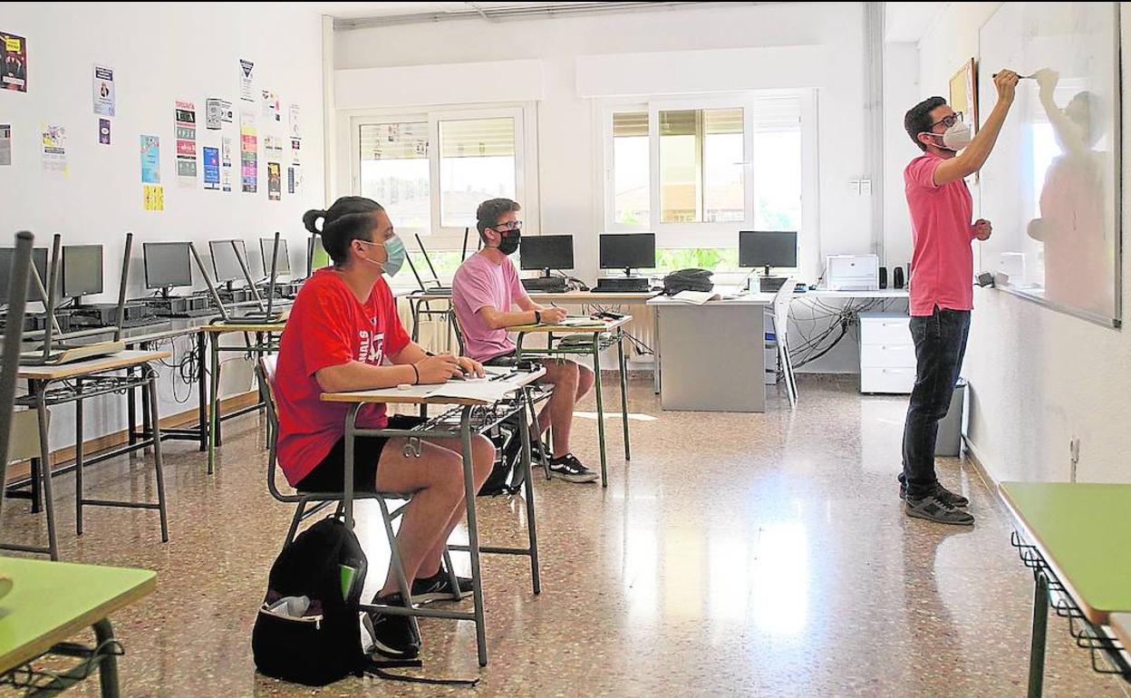 Dos alumnos protegidos con mascarilla siguen la explicación de un profesor en el IES Severo Ochoa de Murcia.