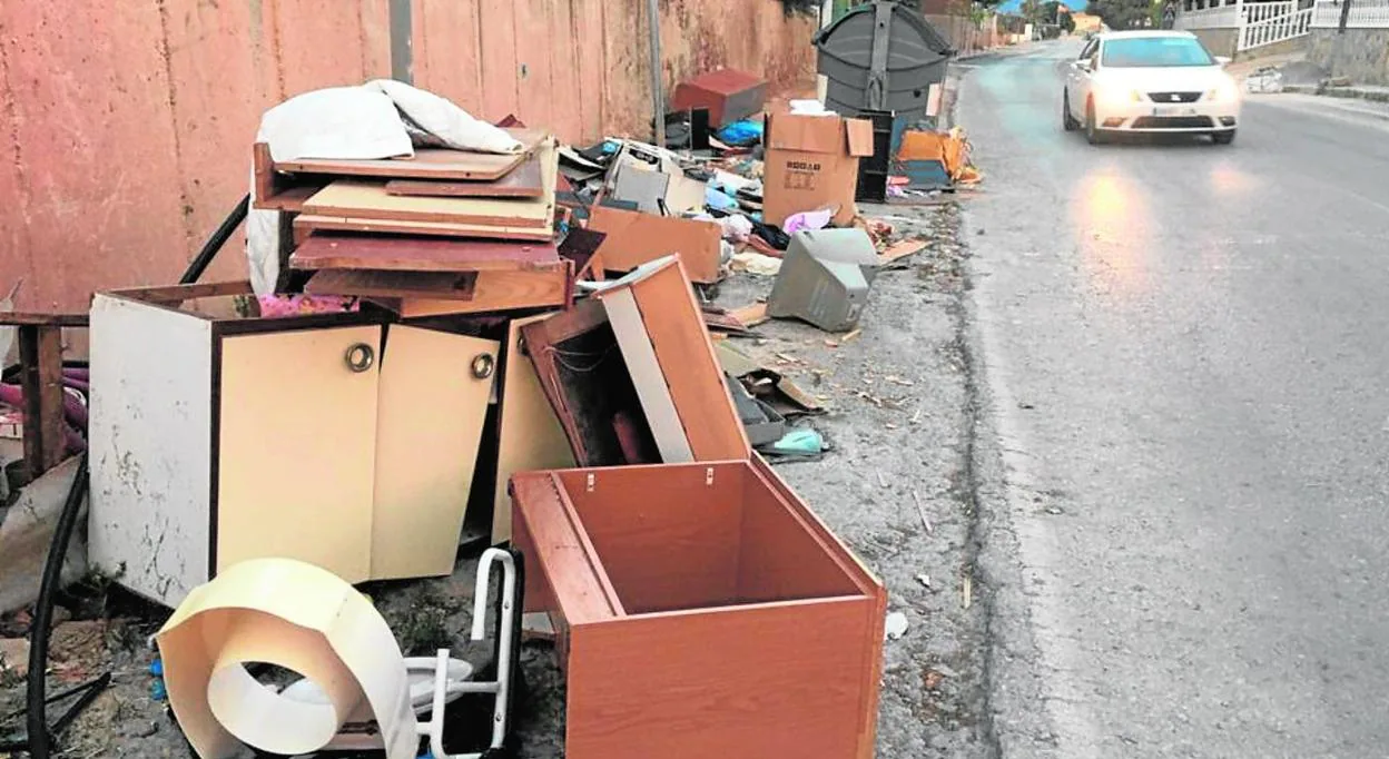 Restos de enseres de viviendas arrojados ilegalmente al lado de un contenedor de residuos, junto a la rambla de Cabezo de Torres. 