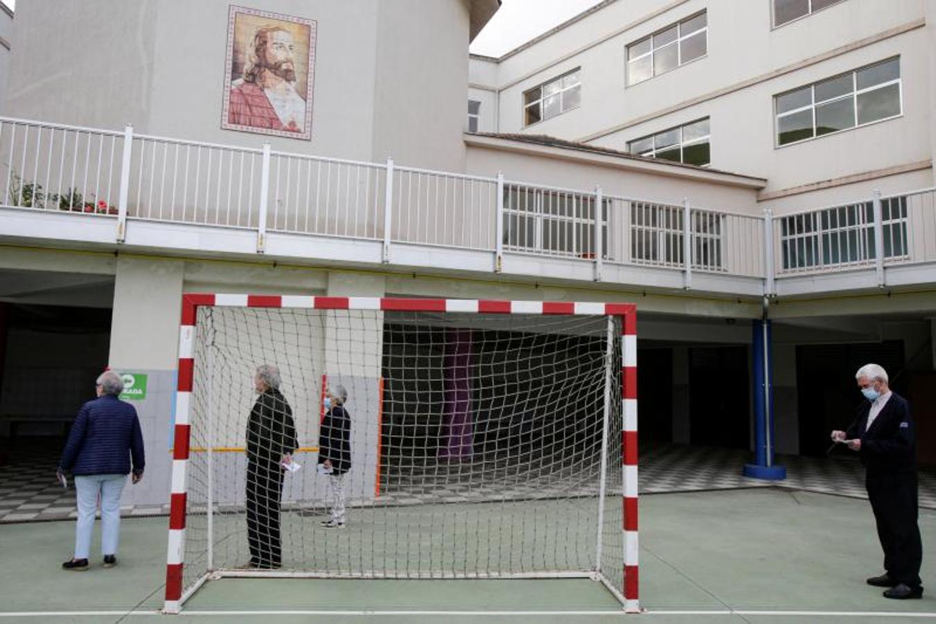 Las personas, que usan mascarillas, aguardan el momento de emitir su voto en un colegio electoral de Ribadeo