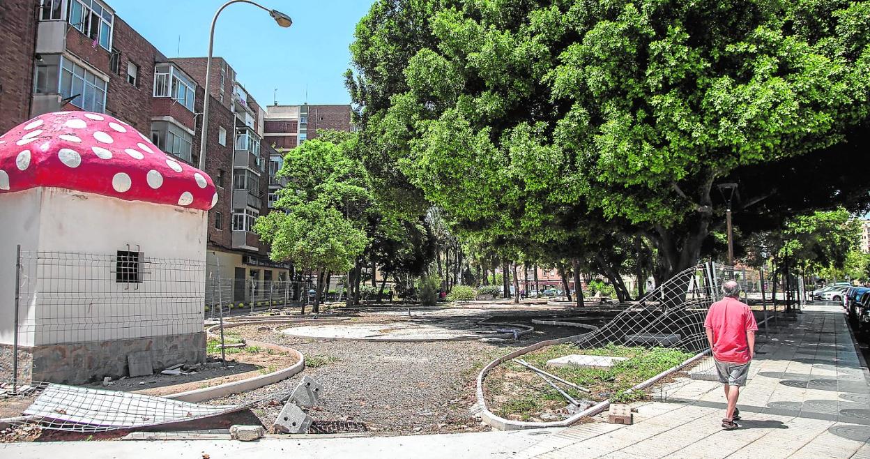 Un hombre pasa junto al vallado derribado y la seta que ha quedado como vestigio de la reforma inacabada en el Parque Sauces. 