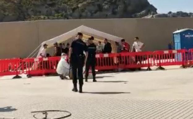 Dos antidisturbios custodian un grupo de argelinos bajo una carpa. La imagen es una captura de un vídeo. 