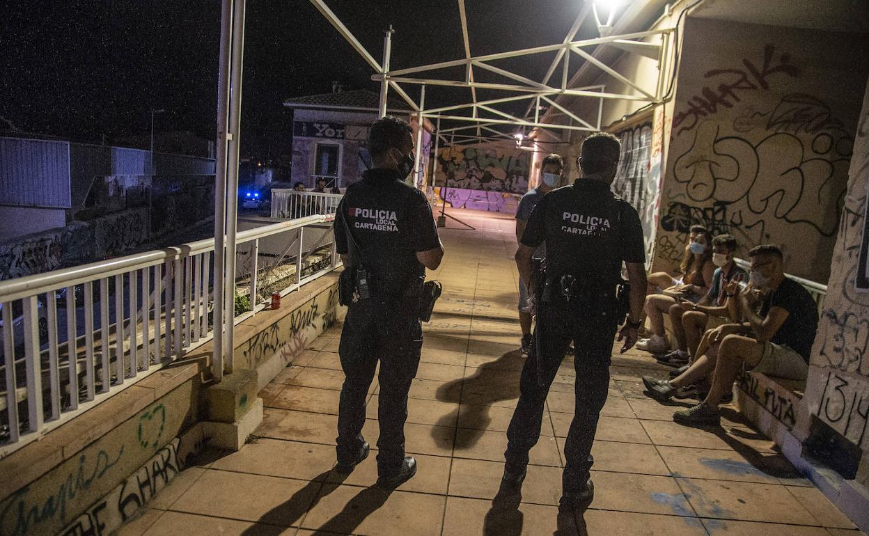 Un inspector y una agente hablan con un joven el sábado por la noche junto a una concurrida terraza de Cabo de Palos.