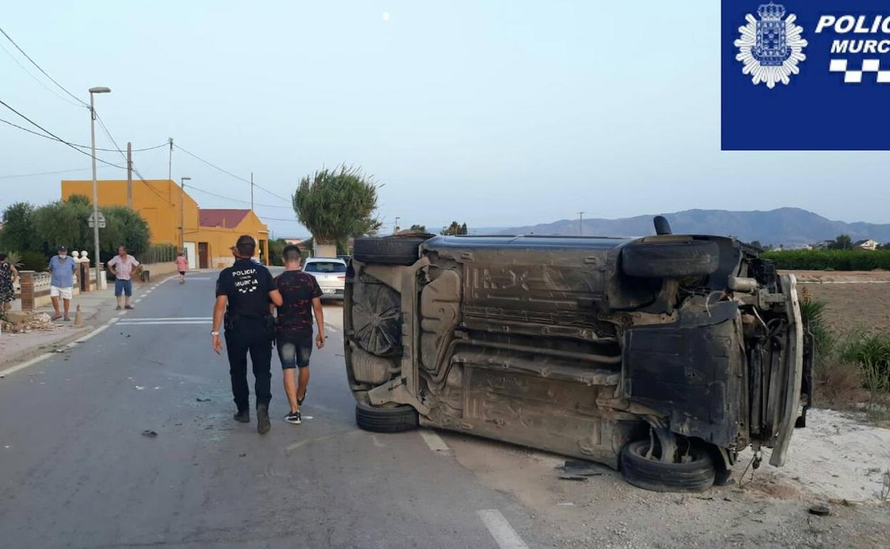 Un agente conduce al detenido, junto al coche que conducía.