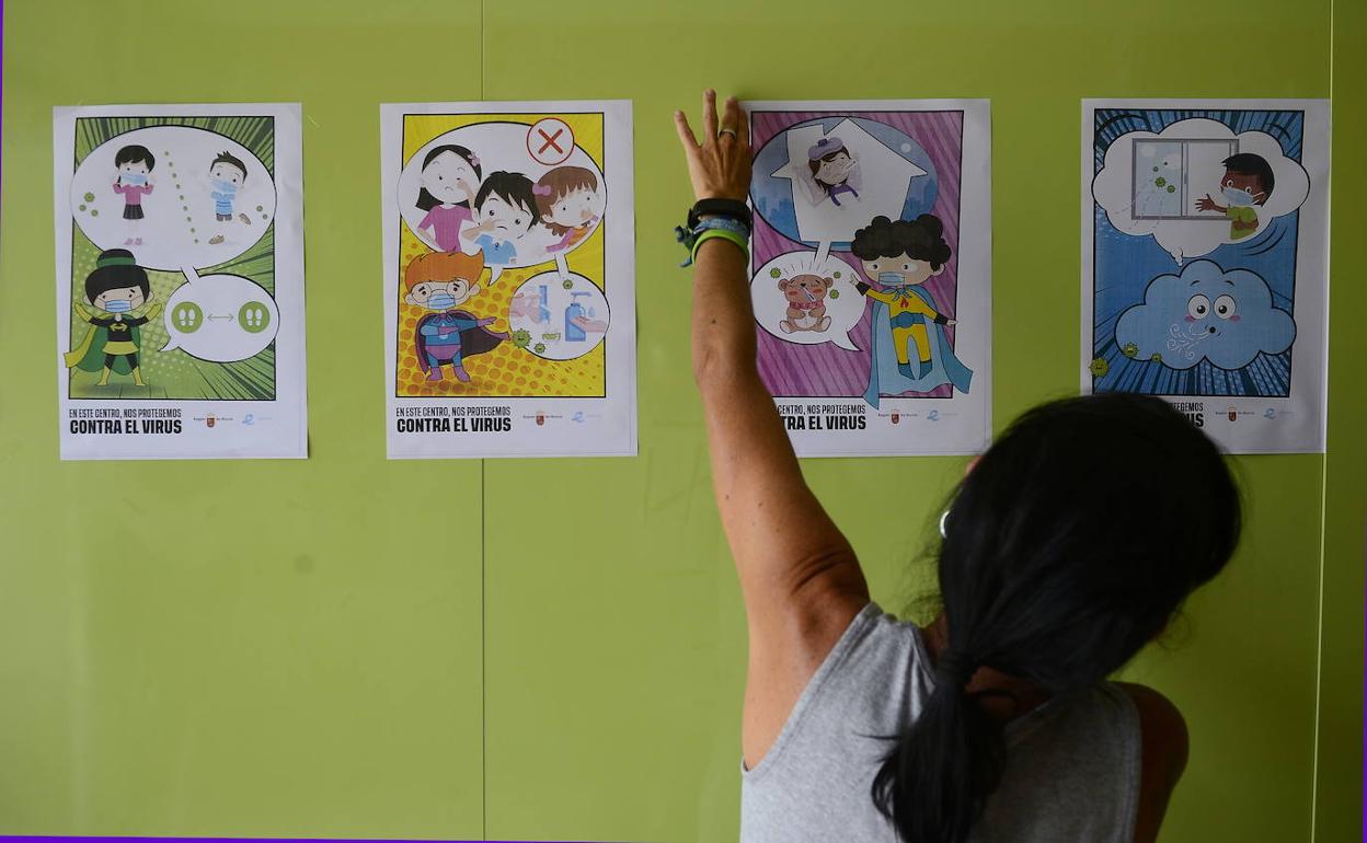 Una empleada del colegio Federico de Arce (Murcia) coloca carteles con indicaciones y medidas de higiene para alumnos y maestros.